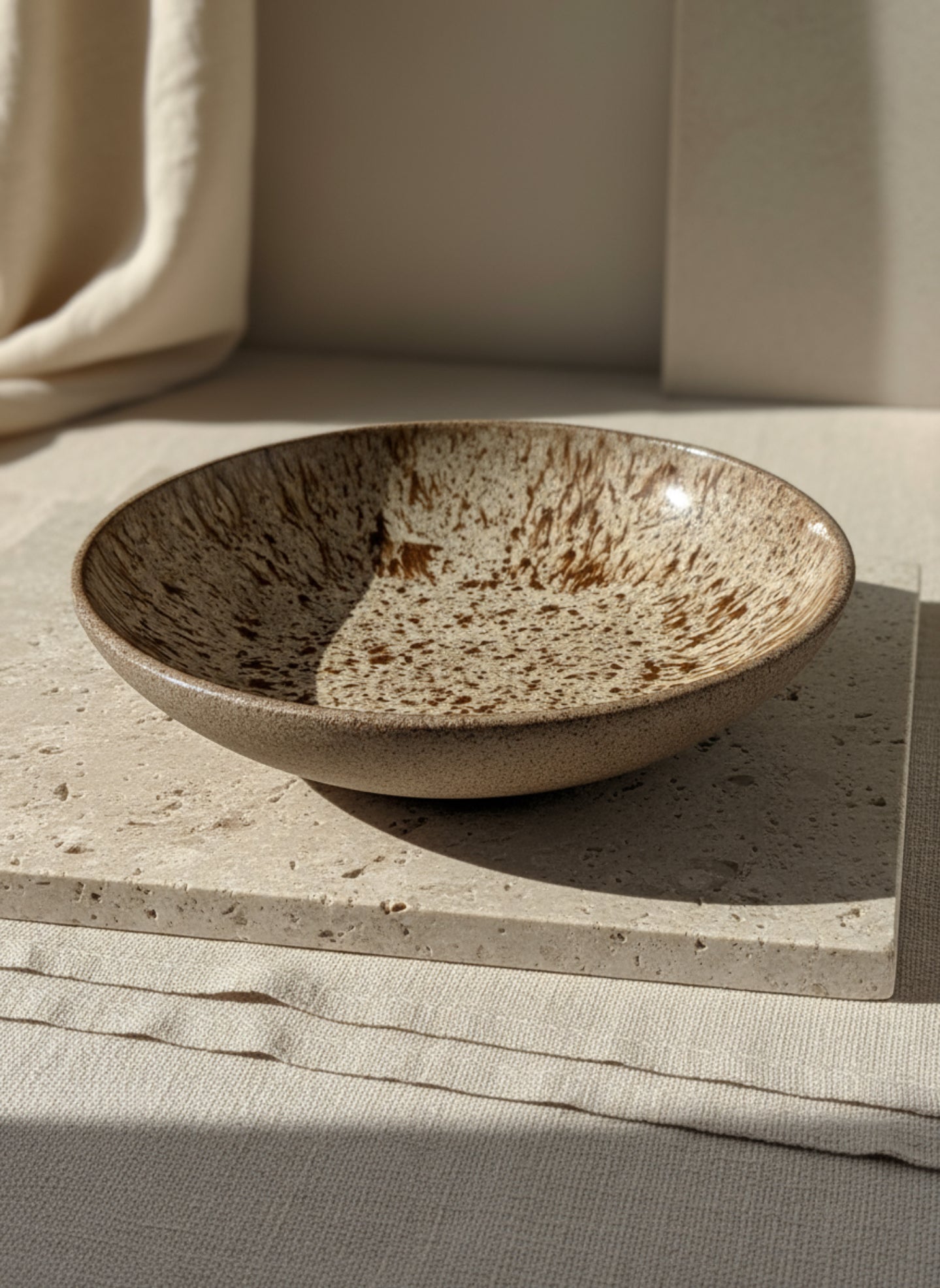 Ceramic bowl with speckled glaze on a white surface