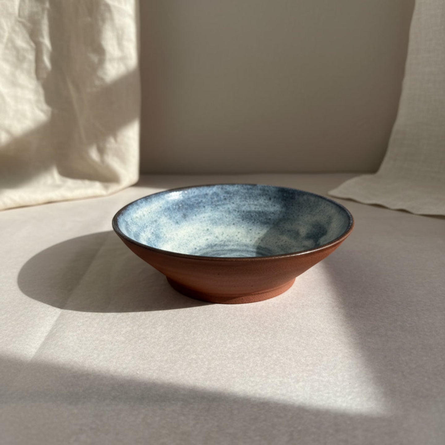 Ceramic bowl with blue and brown glaze on a gray background